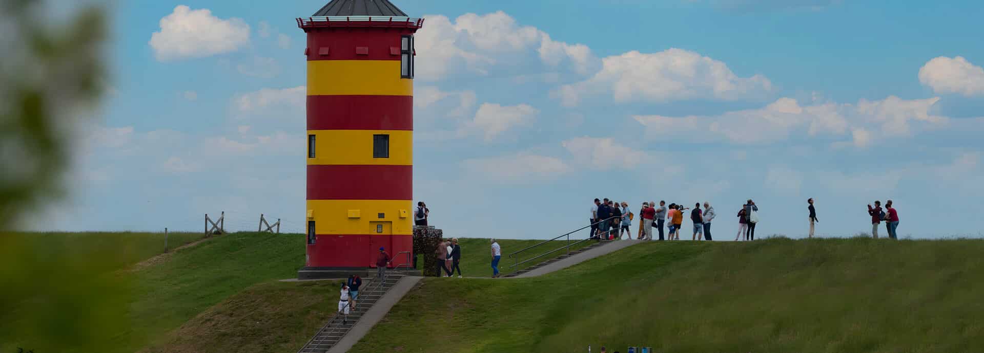 Pilsumer Leuchtturm mit Touristen am Deich