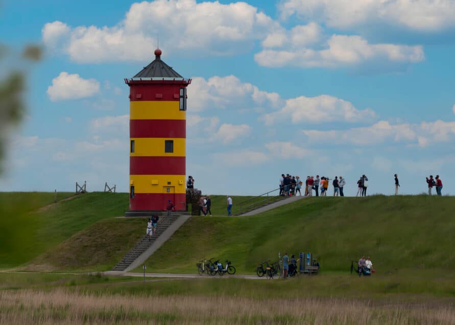 Pilsumer Leuchtturm mit Touristen am Deich